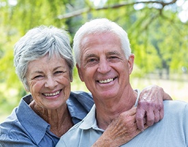 An older couple wearing dentures in Cumming while smiling outside.