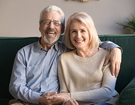 An older couple smiling inside their home.