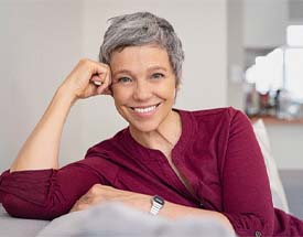 Woman with dentures in Cumming smiling on couch