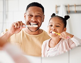 Father and daughter brushing their teeth