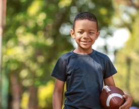 child smiling and holding a football