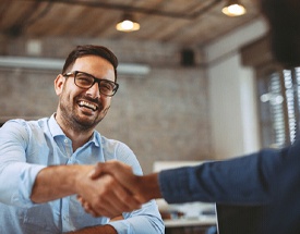 Shaking dentist and patient discuss how to make dental implants affordable in Cumming