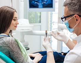  implant dentist in Cumming showing a patient a dental implant