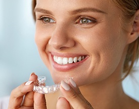 Smiling woman holding Invisalign tray