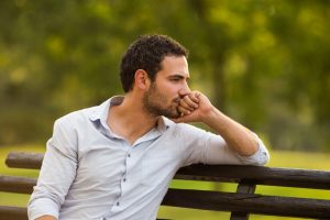 Man contemplating on park bench.