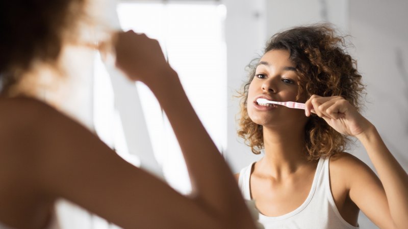 Person smiling while brushing teeth
