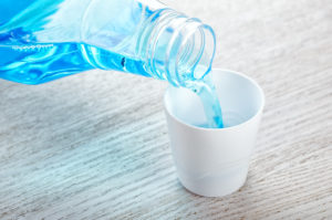 Dentist pouring blue mouthwash into cap