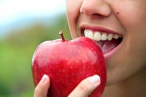 close up of person eating red apple 