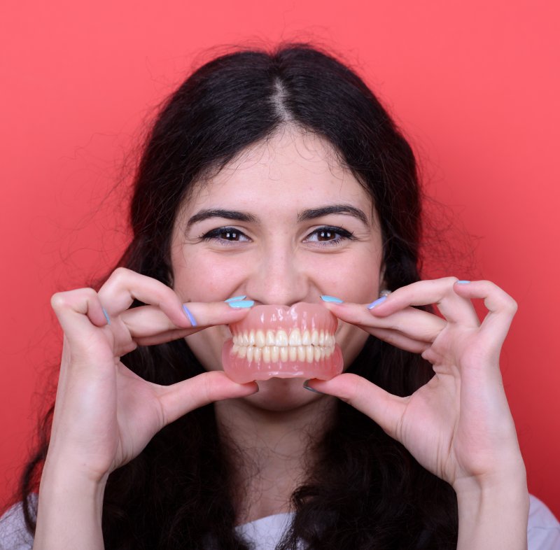 Woman holding dentures in front of her face